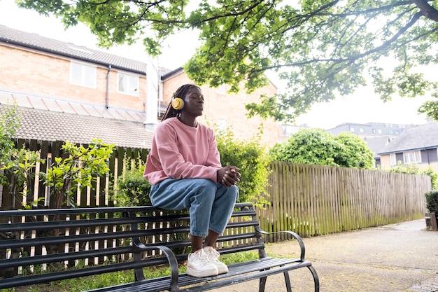 Portrait of young woman with afro dreadlocks listening to music on headphones