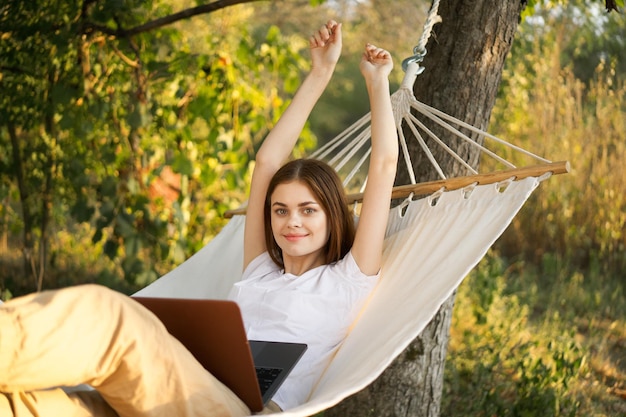 Photo portrait of young woman with arms raised standing against trees