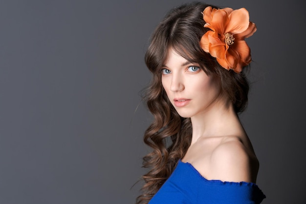 Portrait young woman with an artificial flower in her hair Natural beauty