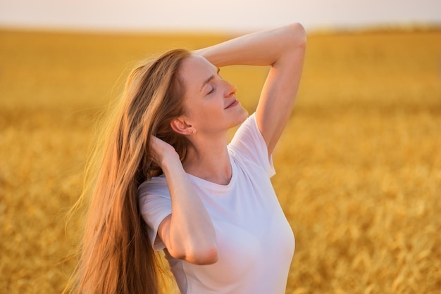 Portrait of young woman with beautiful long hair on wheat field background