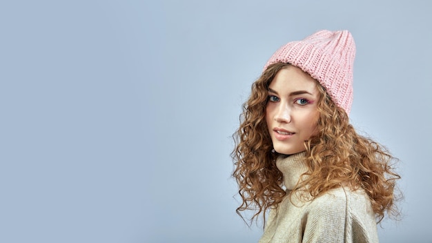 Portrait of a young woman with curly hair in a pink hat