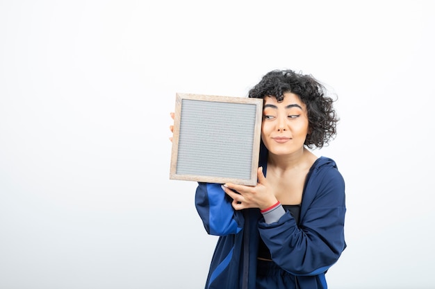 Portrait of a young woman with curly hair with frame standing.