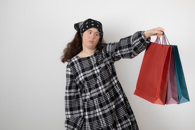 Portrait of young woman with down syndrome holding bunch of shopping bag.