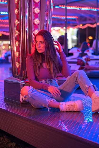 Portrait of a young woman with eyeglasses illuminated by the lights of a fairground