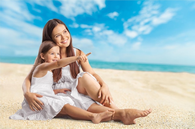 Portrait of young woman with little girl on beach background