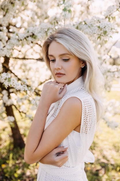 Portrait of a young woman with long blonde hair outdoors in a park