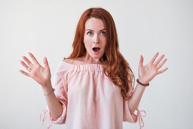 Photo portrait young woman with long curly red hair looking excited holding her mouth opened isolated on white wall