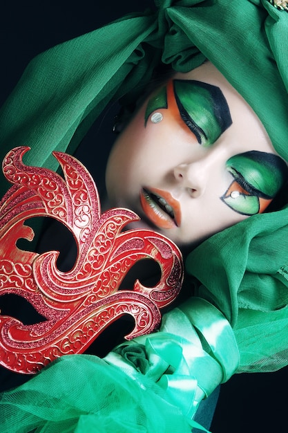 Portrait of young woman with mask in creative theatrical image.