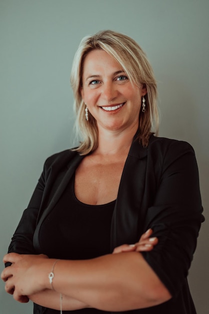 Portrait of a young woman with pleasant smile and crossed arms isolated on grey wall with copy space Beautiful woman with folded arms looking at camera against grey wall Cheerful Hispanic woman