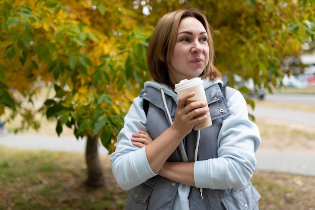 Portrait of a young woman with a slight smile with a glass of coffee against the background of an