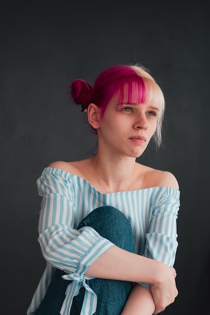 portrait of young woman with white and pink hair on black background