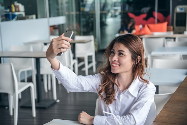 Portraits of Pretty Beautiful Asian woman taking a photo by selfie in urban.