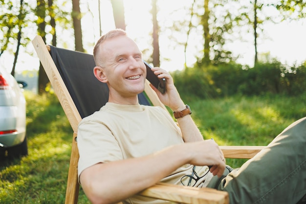 Photo portraits of a young emotional man talking on the phone while sitting in the park recreation in nature remote work weekend in nature