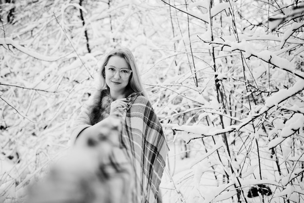 Portraiy of blonde girl in glasses red fur coat and scarf at winter day