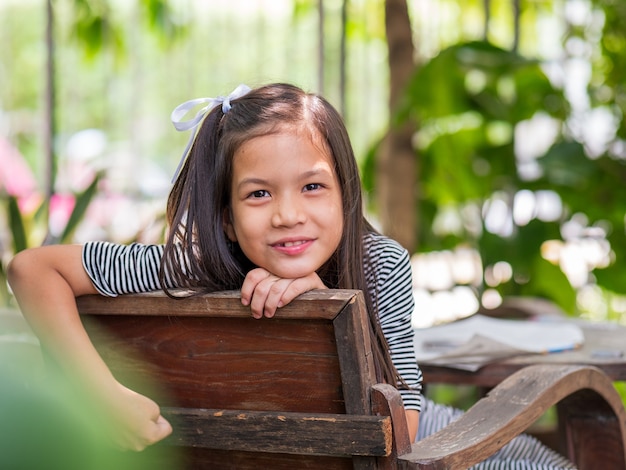 Portriat image of 8 years old Asian girl reading or doing homework at her backyardSchool kid in holiday in the garden