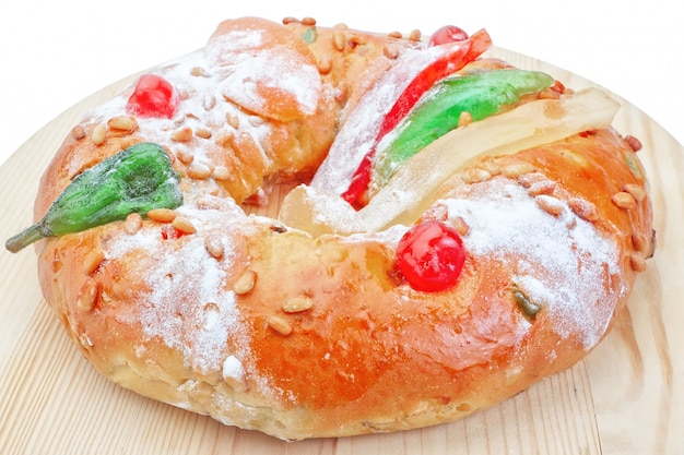 Portuguese king cake on a wooden stand. On a white wall. Close-up.