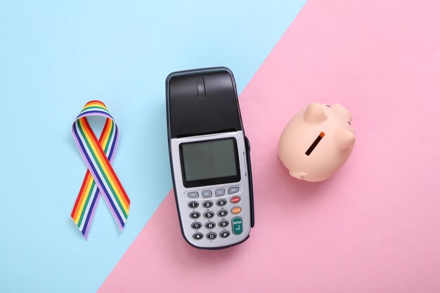 Pos terminal and LGBT rainbow ribbon pride tape symbol piggy bank on pink blue background