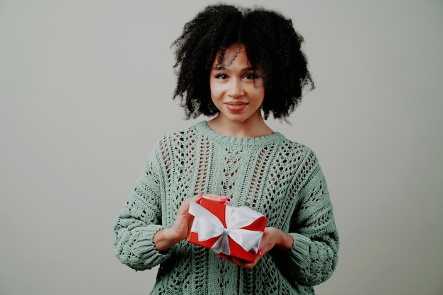 Posing in a photo studio smiling I received a gift in a red box with a bow