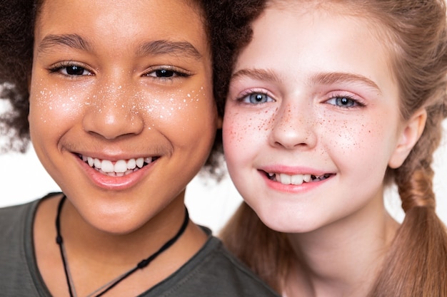 Posing up close. Pleasant good-looking kids displaying their strong white teeth while smiling on camera