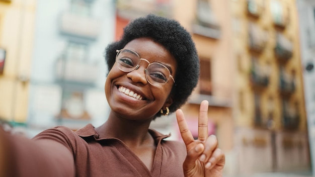 Positive African American dark haired woman taking selfie on str