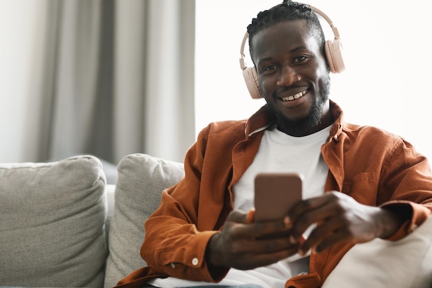 Positive african american man in headset listening to music on cellphone at home selective focus copy space