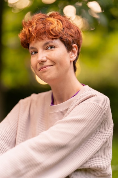 Positive androgynous woman with red hair in nature