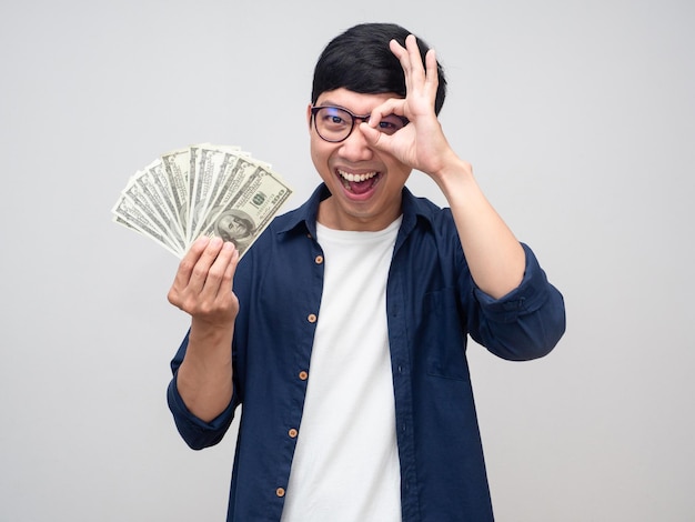 Positive asian man cheerful smile hold money show hand ok isolated