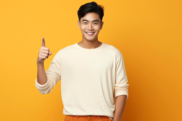 Positive asian man pointing finger aside one color background