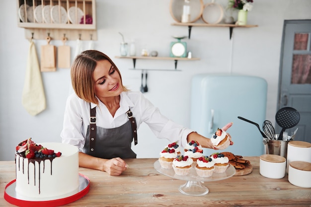 Positive blonde with her homemade delicious cookies and cake in the kitchen.