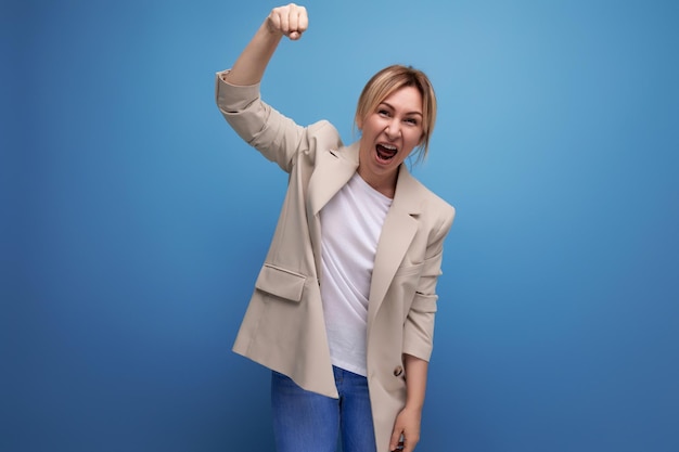 Positive blonde young woman in casual style on studio background