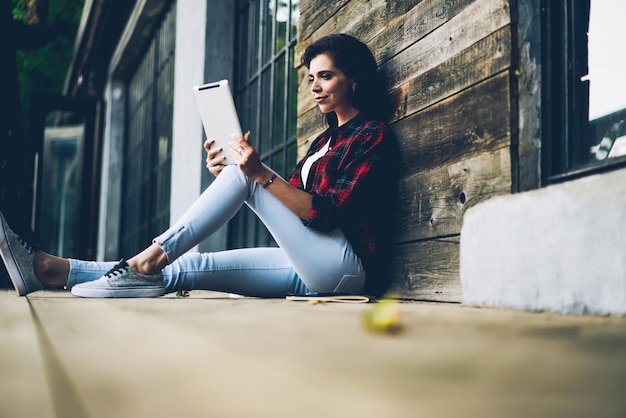 positive brunette woman enjoying recreation while read interesting news in webpage via touch pad