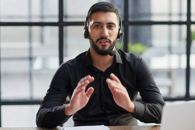 Positive businessman talking on headset at a computer