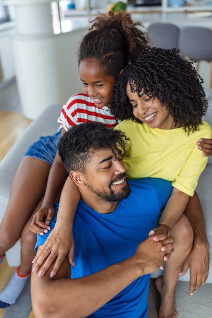 Positive cheerful multiethnic family wife husband child sitting together on couch at home Close up focus on little daughter and beautiful mother Happy multiracial family concep