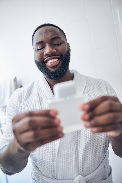 Positive delighted international man keeping smile on his face while preparing for the beginning of working day