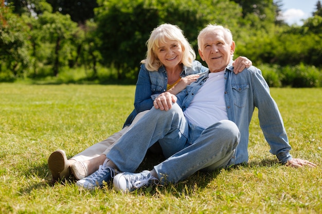 Positive delighted woman keeping smile on her face and putting hands on shoulders