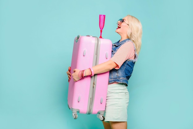 Positive emotion woman with bag pink suitcase on colored background. Travel concept.