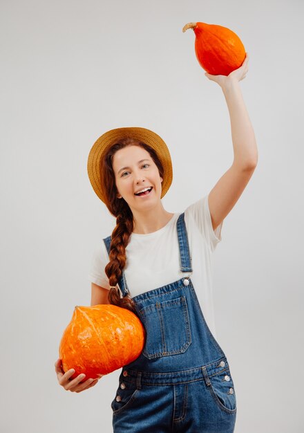 Positive farmer woman holds an autumn harvest of ripe orange pumpkins concept of organic food