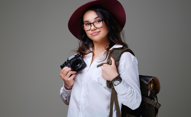 Positive female tourist with photo camera and travel backpack.