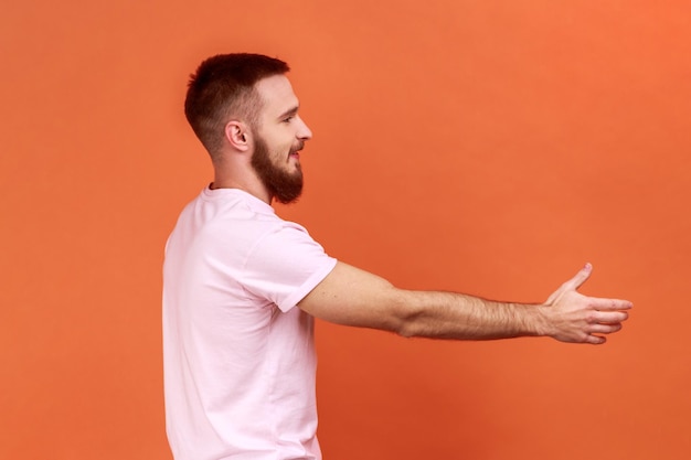 Positive friendly handsome man holding out his hand to side giving handshake