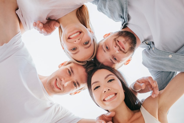 Positive friends holding their heads close to each other and looking down