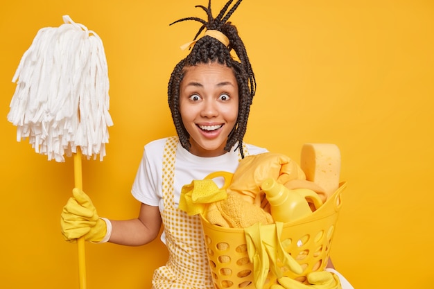 Positive glad Afro American woman poses with mope