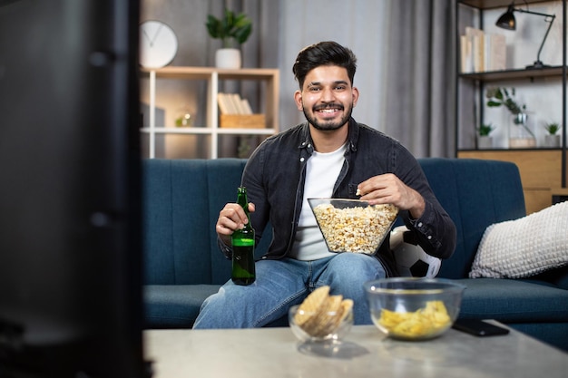 Positive guy with snacks enjoying soccer viewing on TV