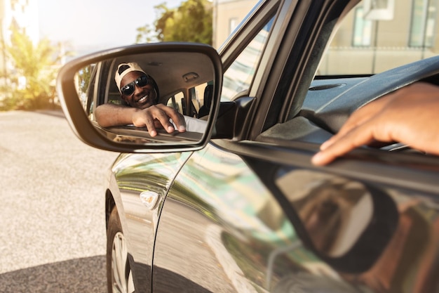 Positive handsome millennial black enjoying car ride