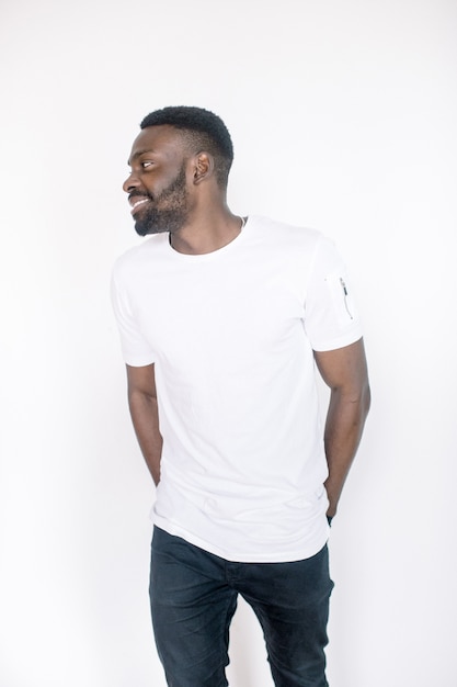 Positive human emotions, facial expressions, feelings, attitude and reaction. Friendly-looking young African American man dressed in white t-shirt and jeans posing in studio on white background