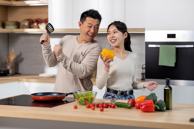 Positive korean man and woman cooking together at home