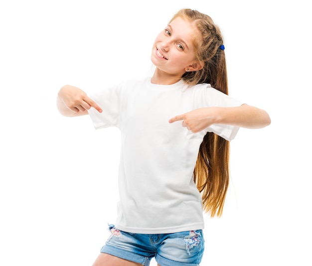 Positive little girl in casual white tshirt indicates at blank space for logo design