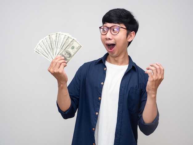 Positive man feels shocked about earn money in his hand isolated