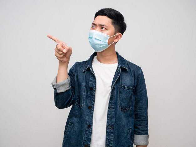 Positive man jeans shirt wear medical mask gesture point finger