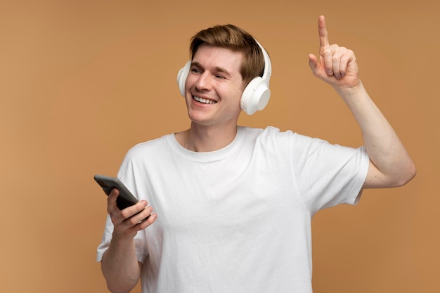 Positive man listening to music or radio on smartphone wearing headset and dancing