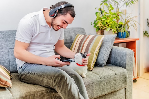 Positive man listening music with headphones seat on sofa